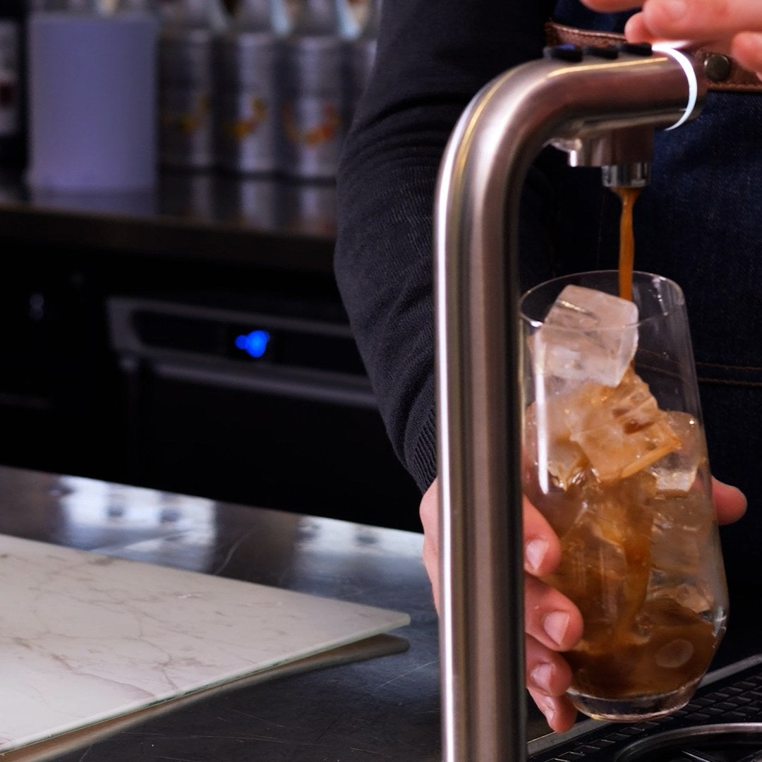 Cold coffee pouring from POUR'D into a glass of ice