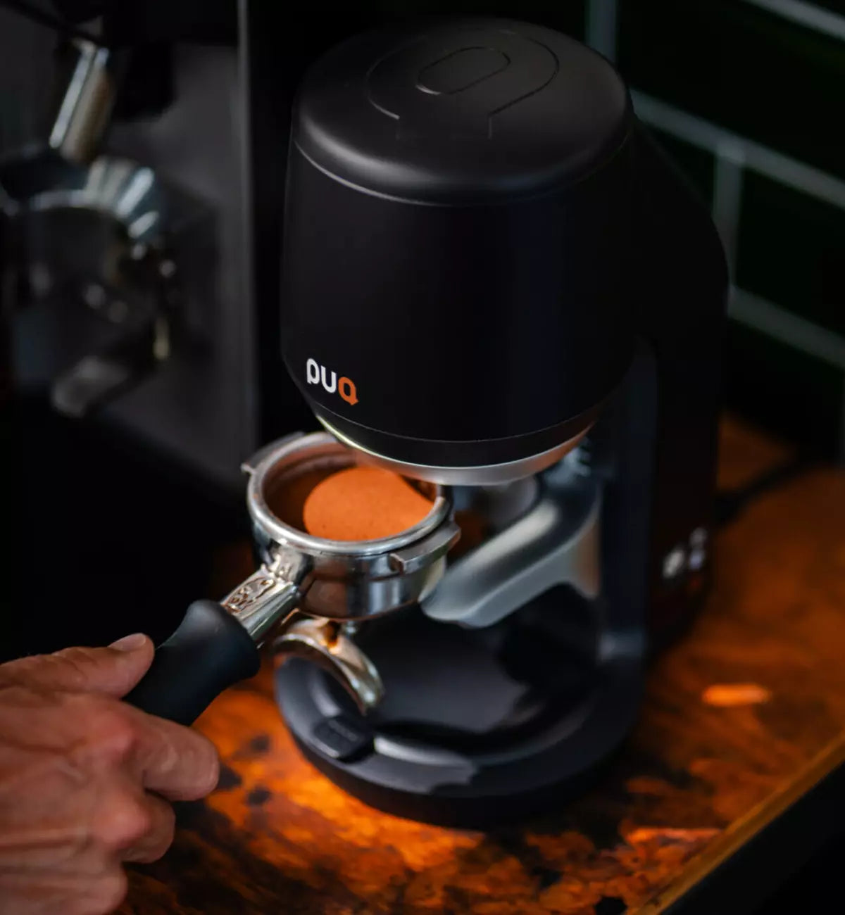 Freshly tamped coffee in a portafilter under a black PUQ Press