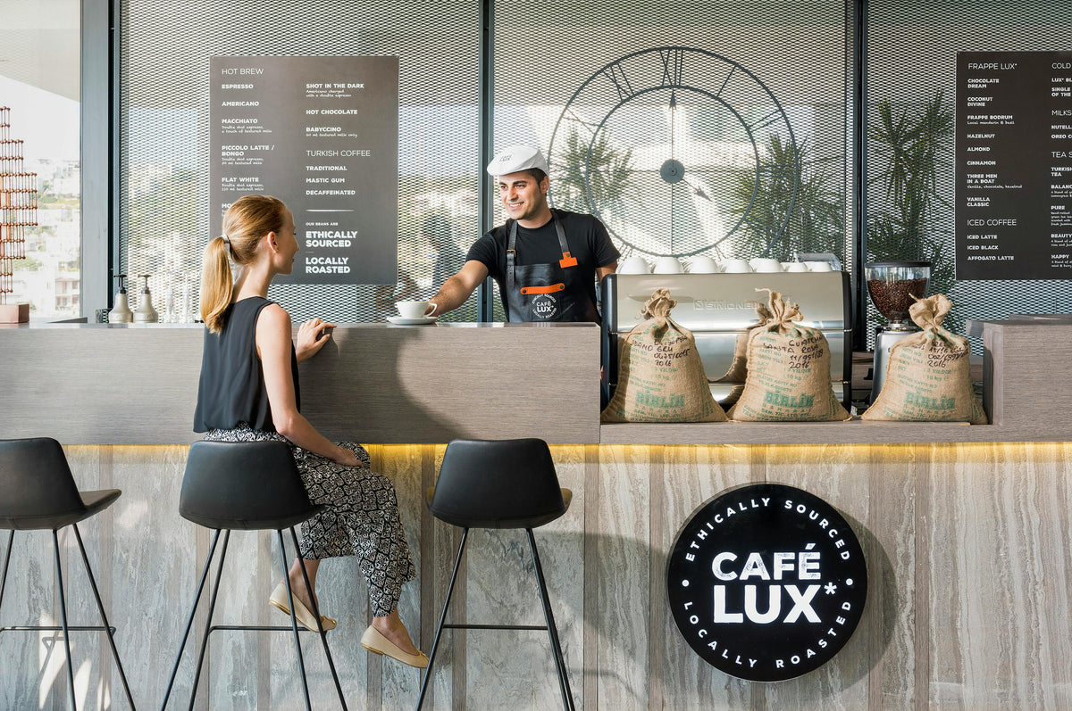 Café Lux coffee shop interior with a customer and staff member at the counter.