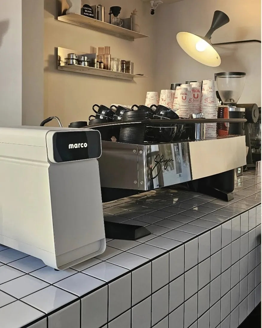 Marco MilkPal beside a Slayer espresso machine on a café counter